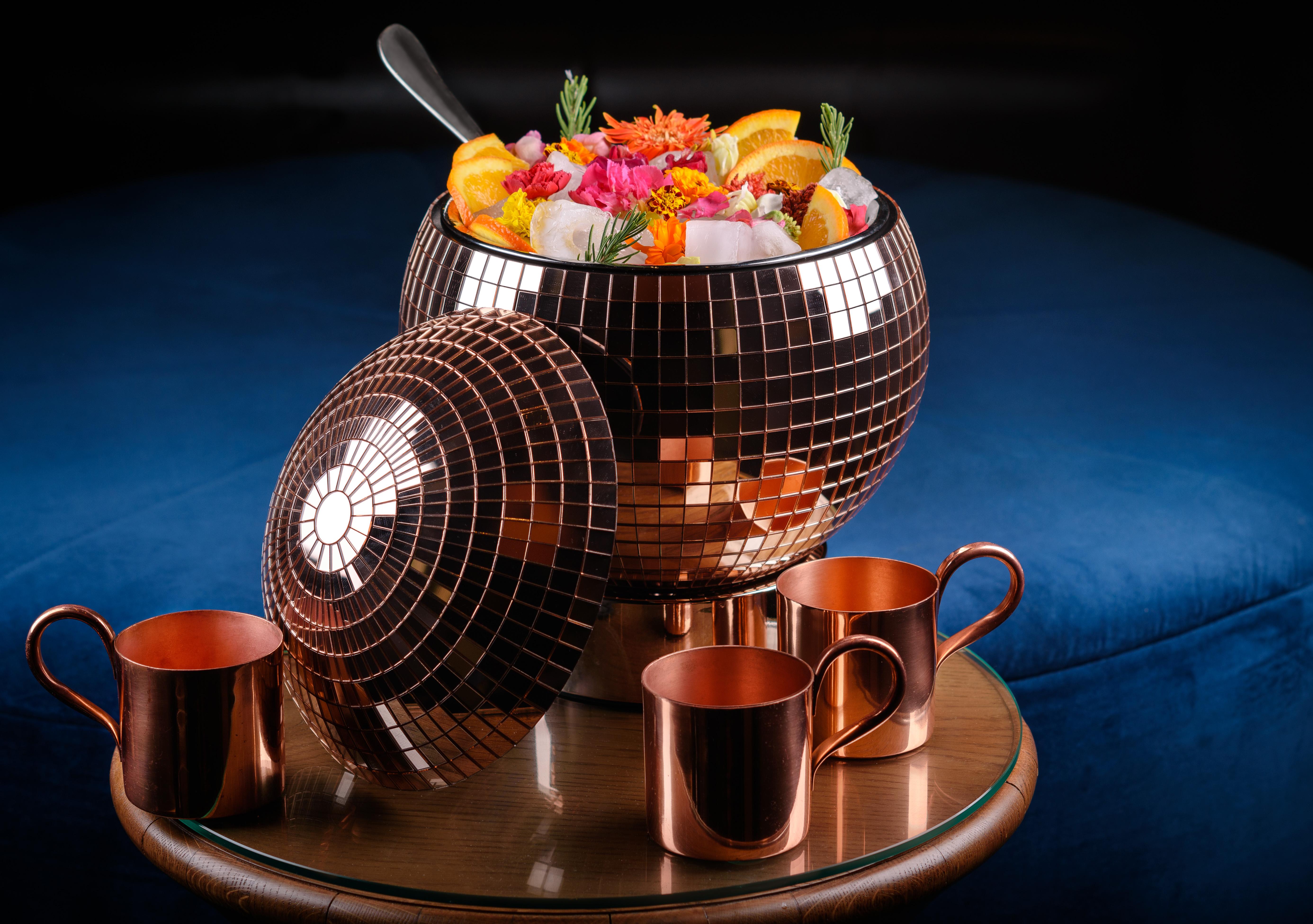 The Palazzo At The Venetian Hotel Las Vegas Exterior photo The photo shows a large, brown, disco-ball-shaped bowl filled with colorful fruits, flowers, and ice. The bowl is shiny and reflective, resembling a disco ball. Surrounding the bowl are four copper cups, which are placed on a round wooden table. The 