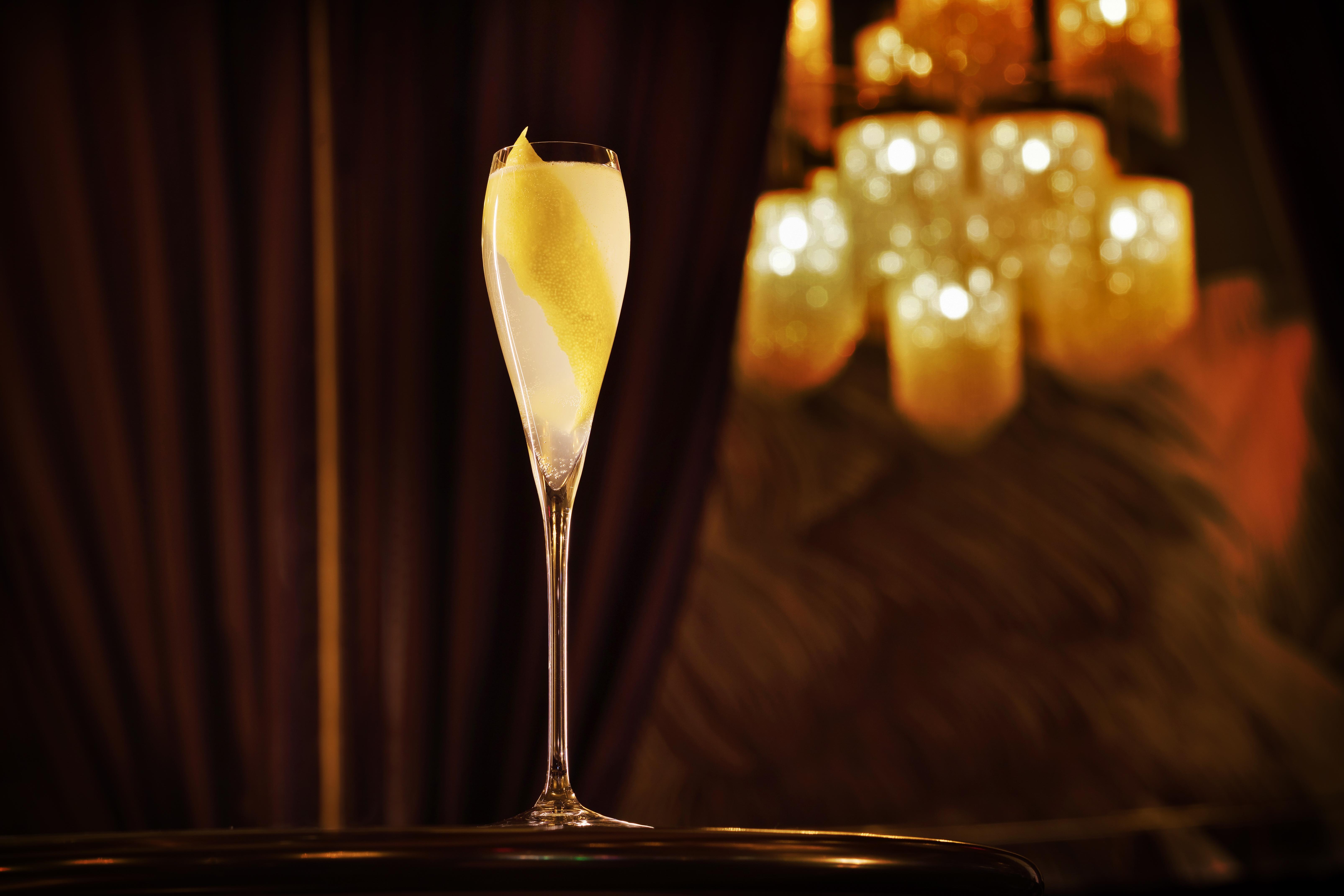 The Palazzo At The Venetian Hotel Las Vegas Exterior photo The photo shows an elegantly arranged champagne flute filled with a light-colored beverage, possibly a cocktail or sparkling wine, featuring a twist of lemon peel as garnish. The glass is set against a backdrop of soft, warm lighting from a chandelie