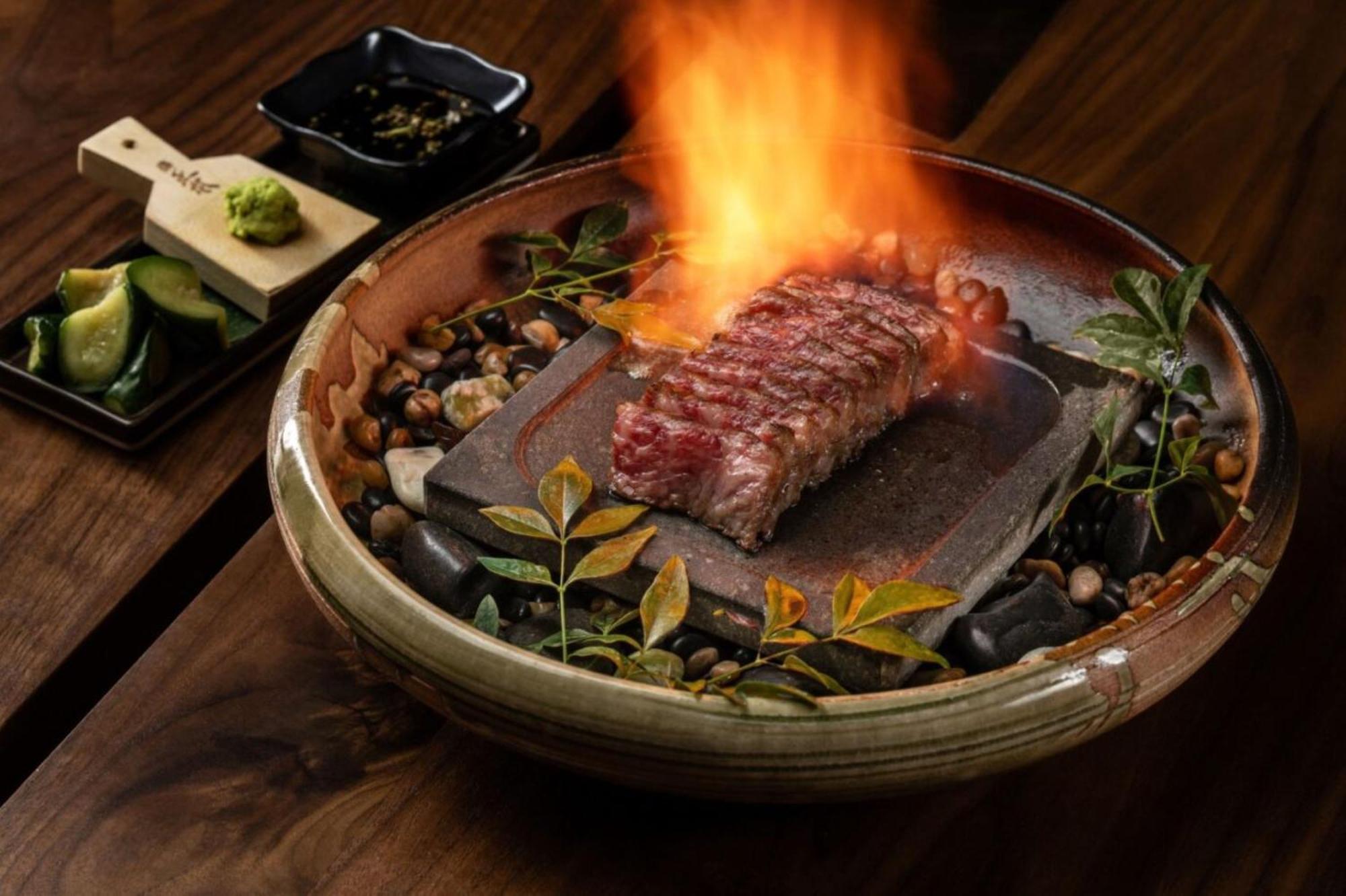 The Palazzo At The Venetian Hotel Las Vegas Exterior photo The photo showcases a beautifully presented dish featuring a large cut of steak, which is placed on a hot stone that is surrounded by decorative elements such as small pebbles and greenery. The steak is ablaze, creating a dramatic visual effect with 