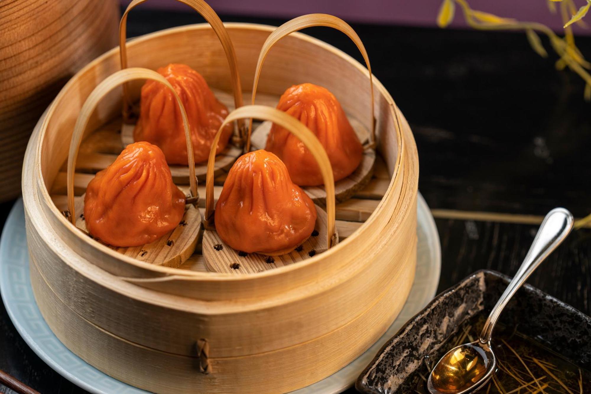 The Palazzo At The Venetian Hotel Las Vegas Exterior photo The photo shows a bamboo steamer containing several dumplings, which appear to be a vibrant orange color. The dumplings are shaped like small pouches with a slightly pleated top, and they are held in place by bamboo strips. The steamer is resting on 